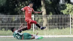 Pemain PS TNI, Ganjar menghalau bola dari kaki pemain Persija Jakarta, Rudi Widodo pada laga uji coba di GOR Ahmad Yani, Cilangkap, Minggu (9/4/2017). PS TNI bermain imbang lawan Persija. (Bola.com/Nicklas Hanoatubun)