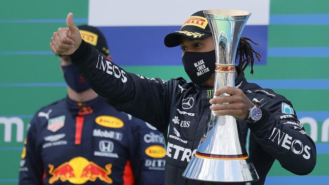 Pembalap Mercedes Lewis Hamilton memegang trofi saat merayakan kemenangannya pada F1 GP Eifel di Nuerburgring, Nuerburg, Jerman, Minggu (11/10/2020). Hamilton dengan 91 kemenangannya menyamai legenda F1 Michael Schumacher. (Ronald Wittek, Pool via AP)