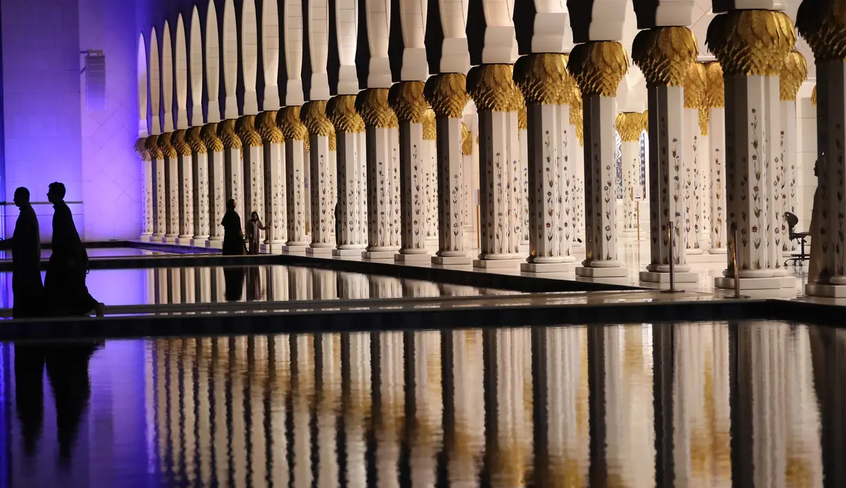 Pengunjung berjalan di lorong Masjid Agung Sheikh Zayed saat persiapan salat tarawih pertama di Abu Dhabi, Rabu (17/5). Masjid ini menjadi destinasi wisata religi dan landmark yang sering didatangi selebriti, turis dan tokoh dunia. (AFP PHOTO/KARIM SAHIB)