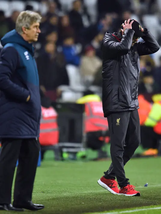 Pelatih Liverpool, Jurgen Klopp memegang kepalanya saat melihat pemainnya bertanding melawan West Ham United pada lanjutan Liga Inggris di The London Stadium (4/2). Hasil ini membuat posisi Liverpool ditempel ketat Manchester City. (AFP Photo/Glyn Kirk)