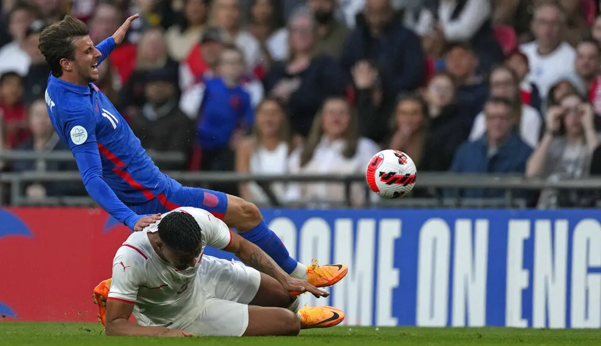 Pemainn Inggris Mason Mount (atas) berebut bola dengan pemain Swiss Manuel Akanji pada pertandingan uji coba di Stadion Wembley, London, Inggris, 26 Maret 2022. Inggris menang 2-1. (AP Photo/Alastair Grant)