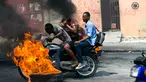 Pengendara sepeda motor melewati barikade ban yang terbakar saat terjadi protes krisis bahan bakar di Port-au-Prince, Haiti, Senin (16/9/2019). Krisis bahan bakar menyebabkan transportasi umum tidak beroperasi. (AP Photo/Dieu Nalio Chery)