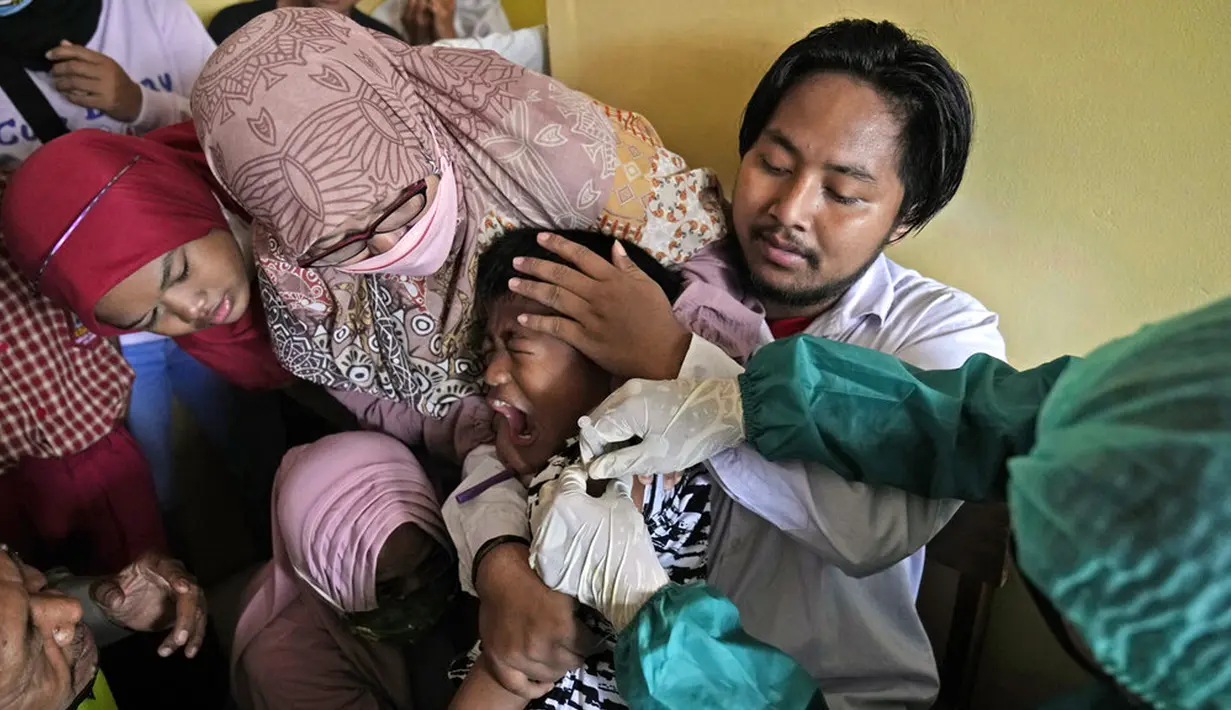 Orangtua, guru, dan polisi mencoba menenangkan seorang siswa saat dia disuntik pada kampanye vaksinasi COVID-19 di sebuah sekolah untuk anak-anak berkebutuhan khusus di Depok, Jawa Barat, Selasa (11/1/2022). Kampanye vaksinasi ini dilakukan oleh Polri. (AP Photo/Dita Alangkara)