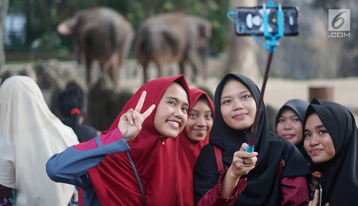 Wisatawan berswafoto saat berlibur di Taman Margasatwa Ragunan (TMR), Jakarta, Kamis (6/6/2019). Setidaknya sebanyak 49.394 warga Ibu Kota dan sekitarnya mengisi libur Lebaran bersama keluarga dengan mengunjungi destinasi liburan murah meriah tersebut. (Liputan6.com/Immanuel Antonius)
