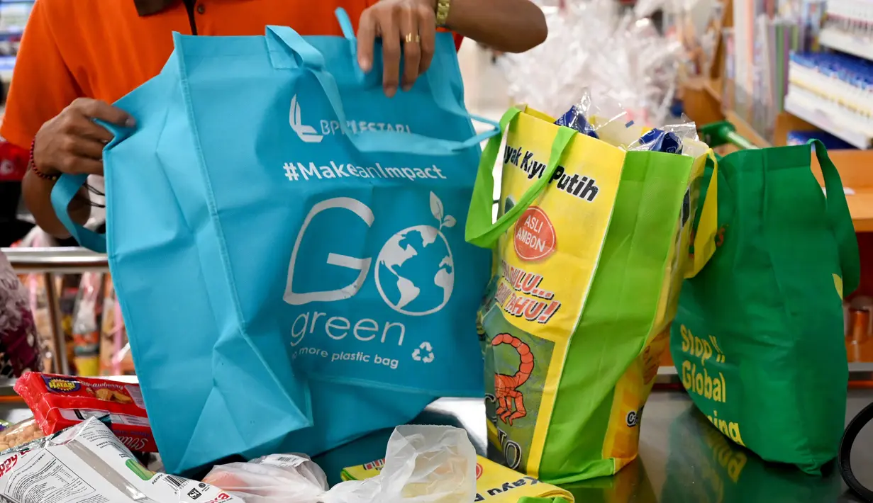 Karyawan mengemas barang belanjaan konsumen dengan tas belanja nonplastik di sebuah supermarket di Denpasar, 16 Juli 2019. Bali menerapkan pelarangan penggunaan plastik sekali pakai yang tertuang dalam Peraturan Gubernur (Pergub) Nomor 97 Tahun 2018. (SONNY TUMBELAKA/AFP)