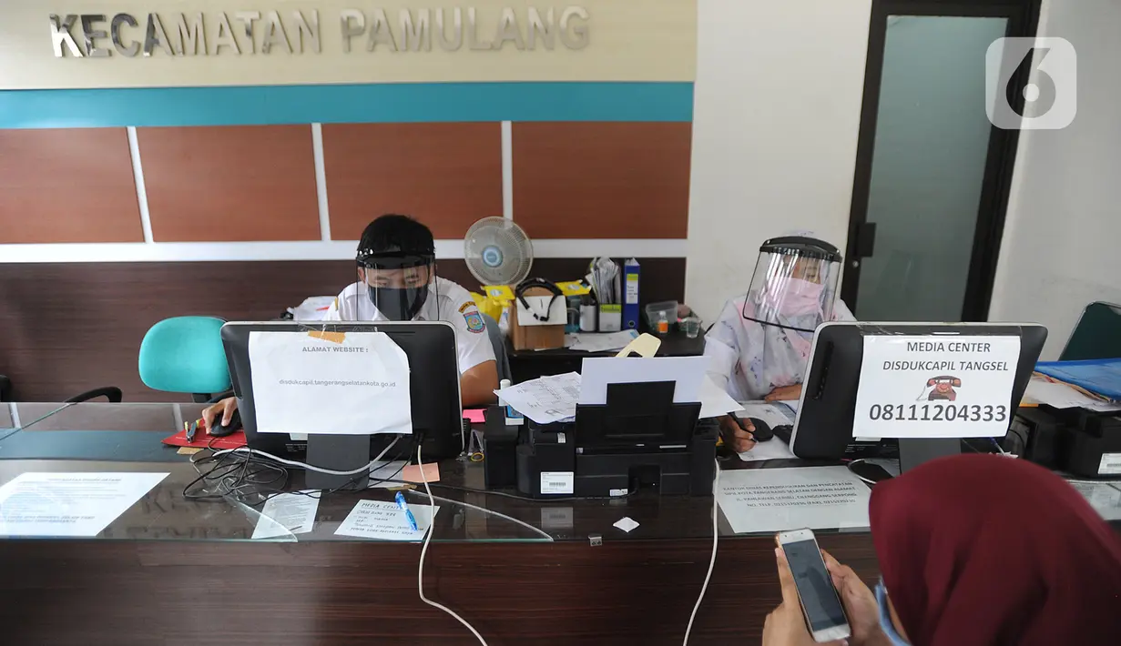 Petugas Dinas Kependudukan dan Catatan Sipil menggunakan pelindung wajah saat melayani warga di Kecamatan Pamulang, Tangerang Selatan, Rabu (3/6/2020). Sejumlah kantor pelayanan pemerintah melaksanakan protokol kesehatan yang ketat untuk memutus rantai penyebaran covid-19. (merdeka.com/Arie Basuki)
