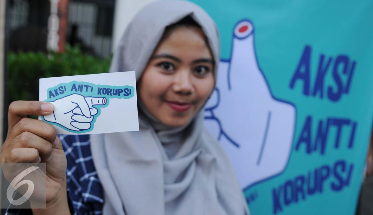 Pengunjung menunjukkan stiker saat Pameran Peringatan Hari Anti Korupsi oleh ICW, Jakarta, Jum’at (9/12). ICW memperingati Hari Anti Korupsi Dunia dengan Pameran instalasi anti korupsi, diskusi dan konser musik. (Liputan6.com/Gempur M Surya)