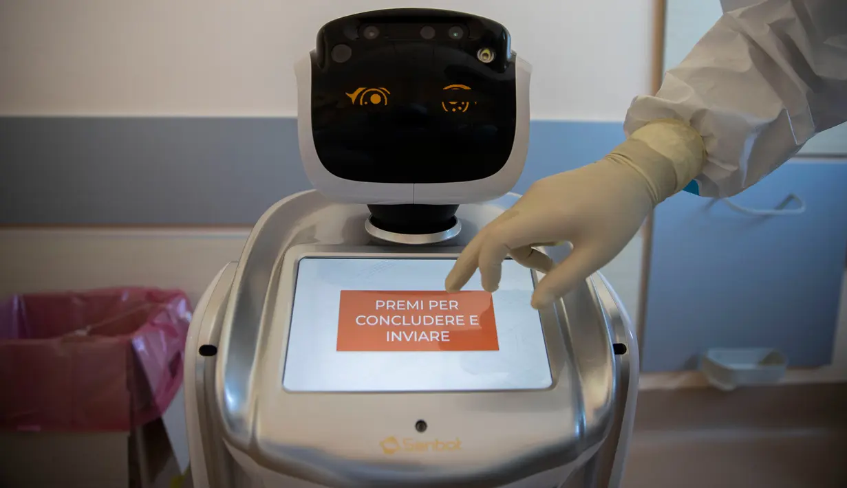 Wakil kepala unit perawatan intensif Flavio Tangian, menggunakan layar sentuh robot di rumah sakit 'Ospedale di Circolo', di Varese, Italia, 8 April 2020. Sebanyak enam unit robot yang berjalan di atas roda ini membantu kinerja staf medis dalam merawat pasien virus corona Covid-19. (AP/Luca Bruno)