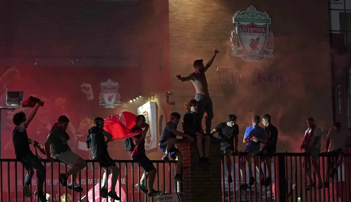 Suporter Liverpool merayakan gelar juara Premier League di depan Stadion Anfield, Kamis (25/6/2020). Titel juara Liga Inggris 2019-20 ini merupakan gelar pertama Liverpool setelah puasa selama 30 tahun. (AP/Jon Super)