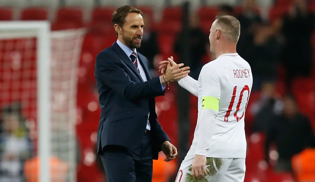 Striker Inggris, Wayne Rooney bersalaman dengan pelatih Gareth Southgate setelah pertandingan persahabatan melawan AS di Stadion Wembley, Inggris (16/11). Rooney telah mencetak 53 gol bersama timnas Inggris. (AFP Photo/Ian Kington)