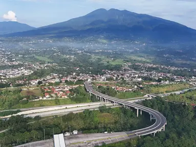 Foto udara memperlihatkan ruas jalan tol Bogor-Ciawi-Sukabumi (Bocimi) dengan latar belakang Gunung Salak di Cicurug, Kabupaten Bogor, Jawa Barat, Selasa (5/11/2024). (merdeka.com/Arie Basuki)