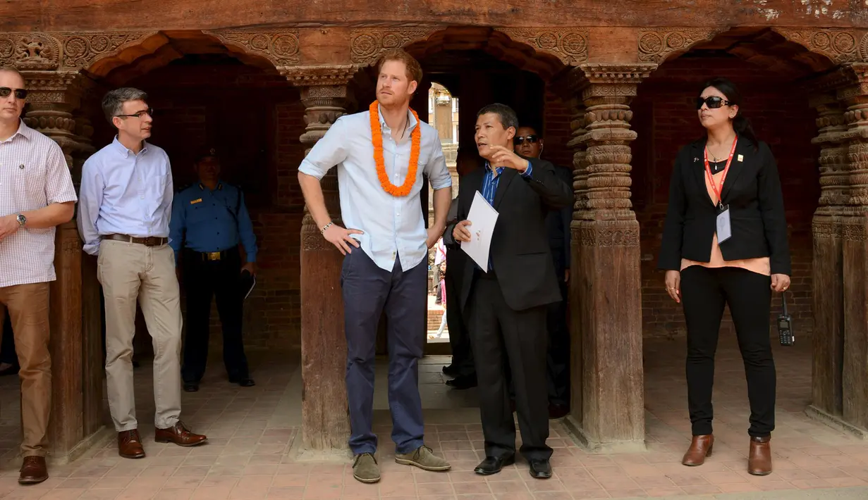 Putra Mahkota Kerajaan Inggris, Pangeran Harry ketika mendengarkan penjelasan mengenai situs warisan dunia, Patan Durbar Square yang turut terkena dampak gempa tahun lalu, di Kathmandu, Nepal, Minggu (20/3). (REUTERS/Prakash Mathema/Pool)