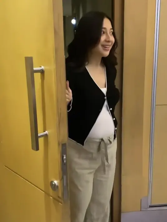 Saat kejutan, Niki mengenakan cardigan hitam dipadukan inner tanktop putih serta celana coklat beige yang memerlihatkan baby bumpnya. Ia juga mengenakan flat shoes hitam putih Chanel. [@sndivia]