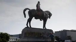 Seorang pria membersihkan coretan pada patung Raja Belgia Leopold II di Brussel, Belgia, Rabu (10/6/2020). Di tengah protes dunia atas kematian George Floyd, patung Raja Leopold II dirusak karena pemerintahannya yang brutal ketika menguasai Kongo ratusan tahun silam. (AP Photo/Virginia Mayo)