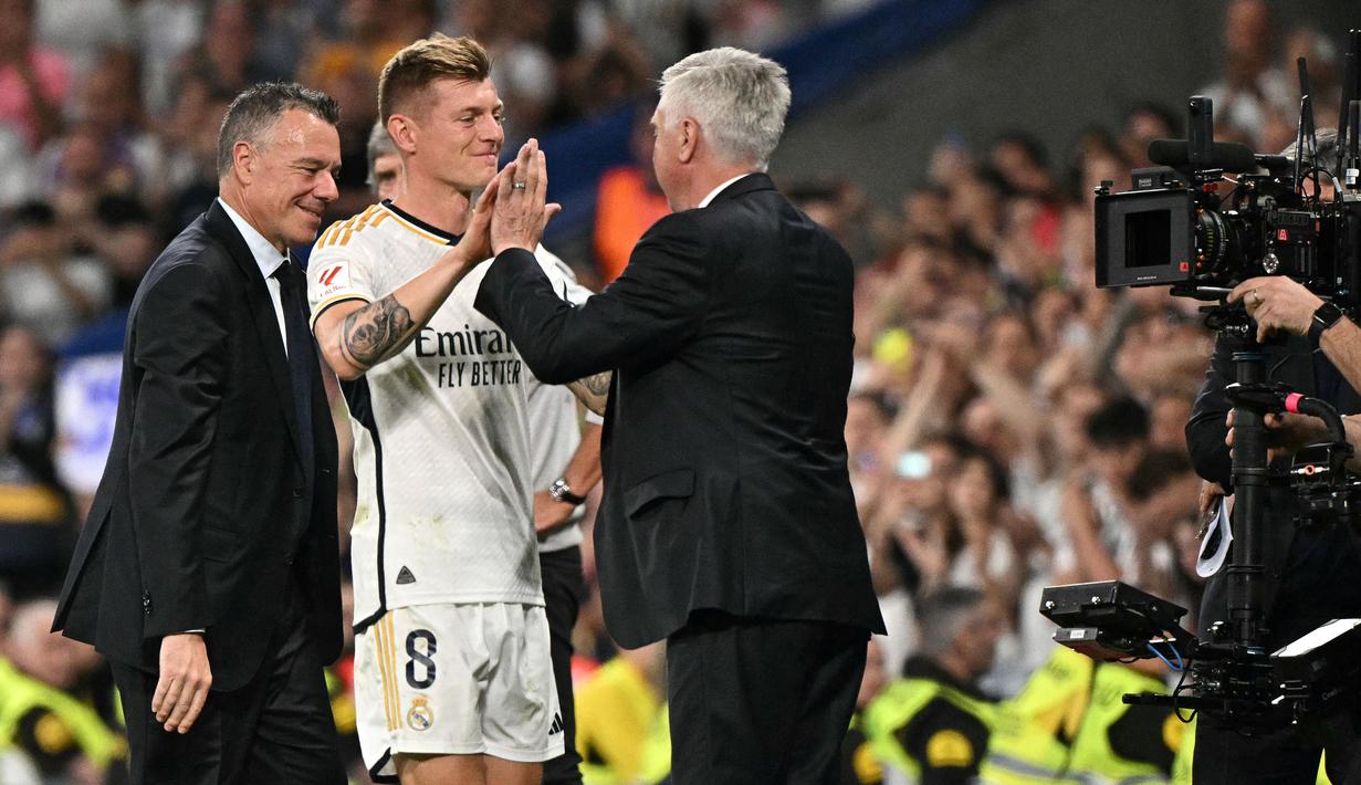 Pemain Real Madrid, Toni Kroos (tengah) menyalami pelatih Carlo Ancelotti saat upacara perpisahan setelah laga Liga Spanyol 2023/2024 melawan Real Betis di Santiago Bernabeu, Madrid, Spanyol, Minggu (26/05/2024) dini hari WIB. Kroos memutuskan untuk pensiun dari sepak bola setelah Euro 2024 nanti. (AFP/Javier Soriano)