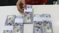 Teller menunjukkan mata uang dolar di Bank Mandiri, Jakarta, Kamis (10/1). Nilai tukar rupiah terhadap dolar Amerika Serikat (AS) terus menguat di perdagangan pasar spot hari ini. Rupiah berada di zona hijau. (Liputan6.com/Angga Yuniar)