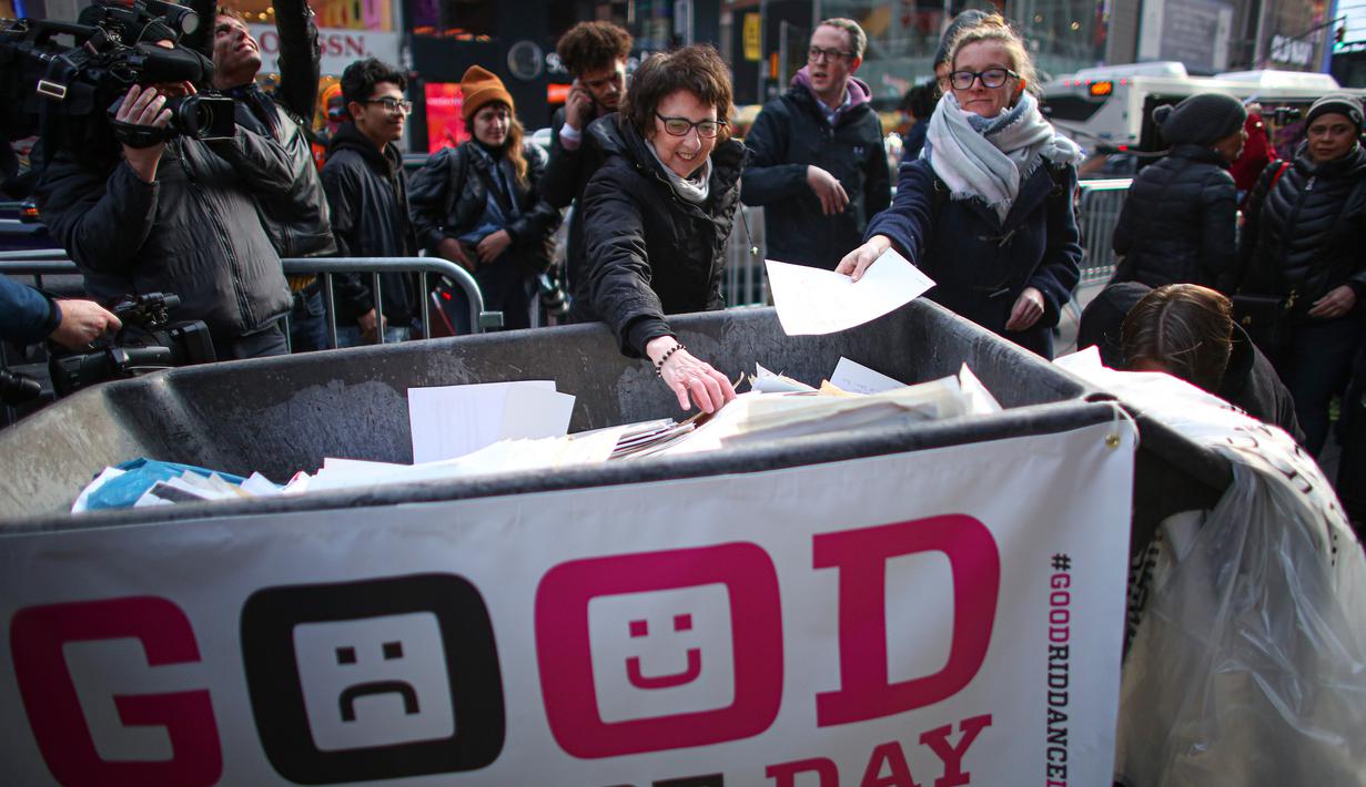 Seorang perempuan melempar kertas berisi kenangan menyulitkan ke tempat sampah selama kegiatan Good Riddance Day ke-13 tahunan di Times Square, New York, 28 Desember 2019. Kegiatan menjelang tahun baru tersebut menjadi tradisi untuk menghapus kenangan buruk selama satu tahun. (Kena Betancur / AFP)