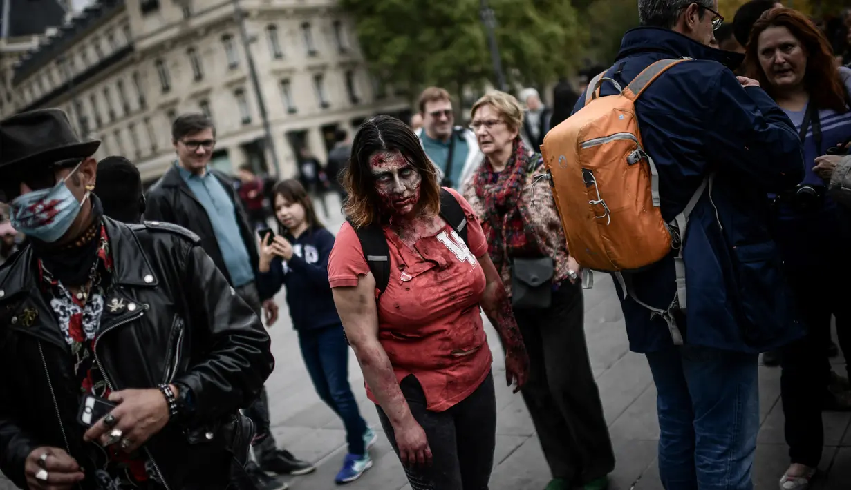 Penggemar film horor menggunakan riasan zombie saat mengikuti acara Zombie Walk di Place de la Republique, Paris, Sabtu (12/10/2019). Sejak 2008, acara Zombie Walk digelar untuk orang-orang yang terobsesi dengan mayat hidup. (Martin BUREAU / AFP)