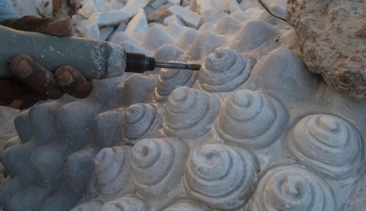 Seorang pekerja memahat patung Buddha yang terbuat dari batu marmer di desa Sagyin, Madaya, Myanmar pada 22 Desember 2018.  Patung-patung marmer yang diproduksi di desa Sagyin ini diekspor ke Thailand, Vietnam, dan Taiwan. (YE AUNG THU / AFP)