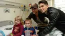 Pemain Barcelona, Marc Bartra (kiri) dan Neymar berpose dengan pasien anak saat melakukan kunjungan amal di Rumah Sakit Vall d' Hebron, Barcelona, Senin (4/1/2016). (AFP PHOTO / Josep LAGO)