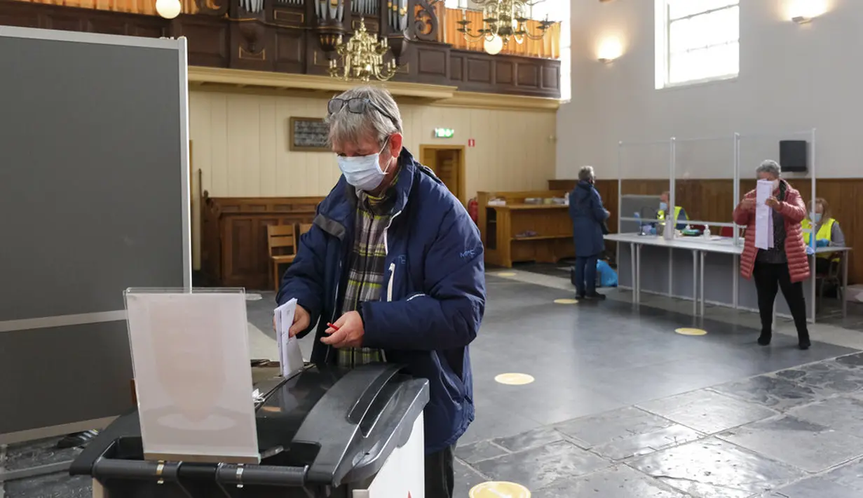 Warga memberikan suara dalam pemilihan umum di sebuah gereja di Desa Ransdorp, dekat Amsterdam, Belanda, Rabu (17/3/2021). Pemilu digelar selama tiga hari untuk memungkinkan warga memilih dengan aman selama pandemi virus corona COVID-19. (AP Photo/Patrick Post)
