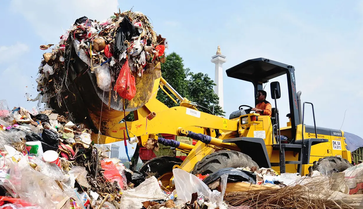 Alat berat milik dinas kebersihan Pemprov DKI Jakarta diterjunkan untuk mengenyahkan gunungan sampah yang ada di kawasan Monumen Nasional, Jakarta, (31/7/2014). (Liputan6.com/Faizal Fanani)