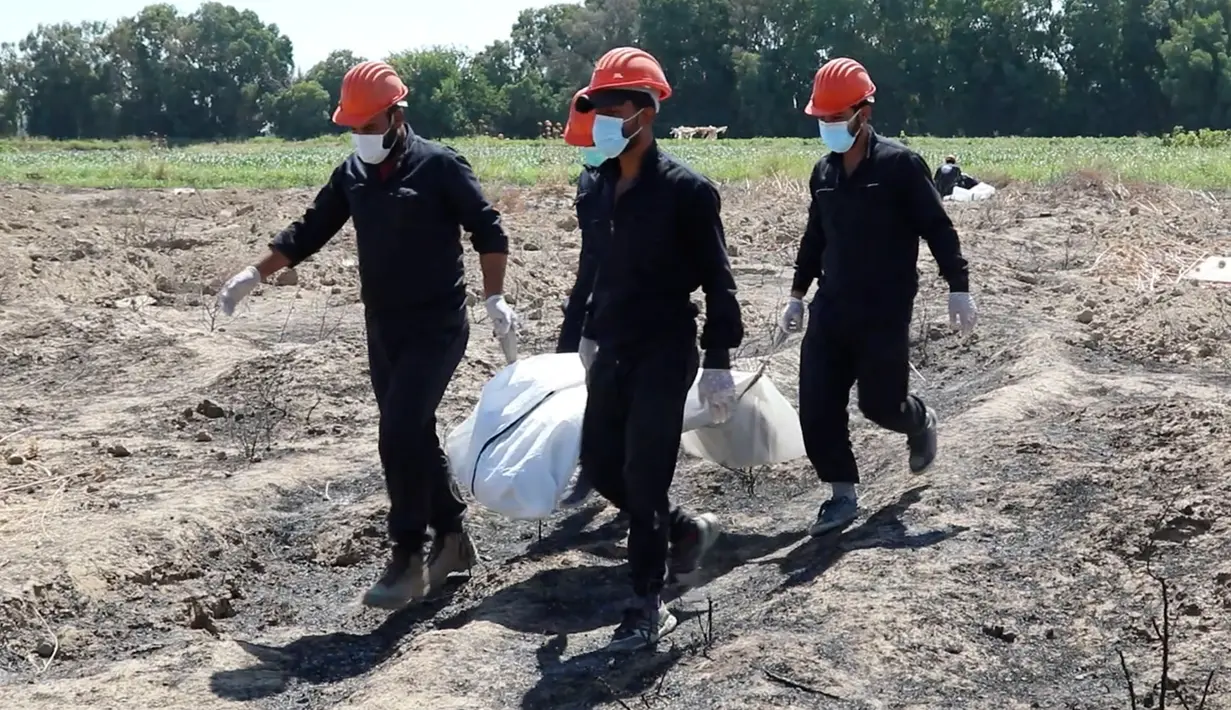Pekerja Dewan Sipil Raqqa memindahkan tulang belulang manusia di kuburan massal yang ditemukan di Raqqa, Suriah, 14 Juli 2019. Di antara jasad-jasad yang ditemukan merupakan warga sipil termasuk perempuan dan anak-anak, diyakini merupakan  orang-orang yang telah ditembak mati militan ISIS (AP Photo)