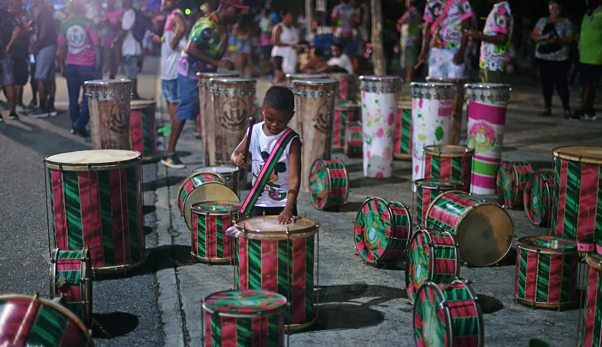 Seorang anak lelaki bermain dengan drum sebelum sesi latihan oleh sekolah samba Mangueira di Rio de Janeiro (21/2). Karnaval Rio de Janeiro akan berlangsung dari 2 Maret hingga 9 Maret 2019. (AFP Photo/Carl De Souza)