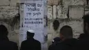 Orang-orang Yahudi berdiri di depan poster dalam bahasa Ibrani dan Tiongkok mengatakan, "Bangsa Israel berdoa untuk China." saat berdoa di Tembok Ratapan, situs paling suci di Kota Tua Yerusalem, Minggu, (16/2/2020). (AP Photo/Ariel Schalit)