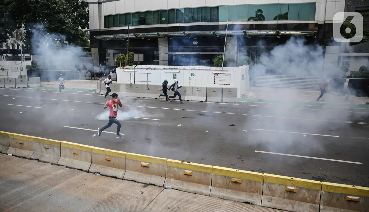 Pengunjuk rasa tolak UU Cipta Kerja bentrok dengan polisi di sekitar Patung Kuda, Jakarta Pusat, Selasa (13/10/2020). Gas air mata ditembakkan ke arah pendemo yang melakukan perlawanan dengan melempar batu dan pecahan kaca. (Liputan6.com/Faizal Fanani)