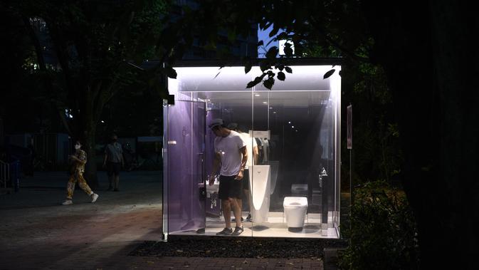 Seorang pria menggunakan toilet transparan di Haru-no-Ogawa Community Park di distrik Shibuya, Tokyo (19/8/2020). Toilet ini dirancang oleh Shigeru Ban dimana dinding luar kacanya akan berubah menjadi buram ketika kuncinya ditutup. (AFP Photo/Philip Fong)