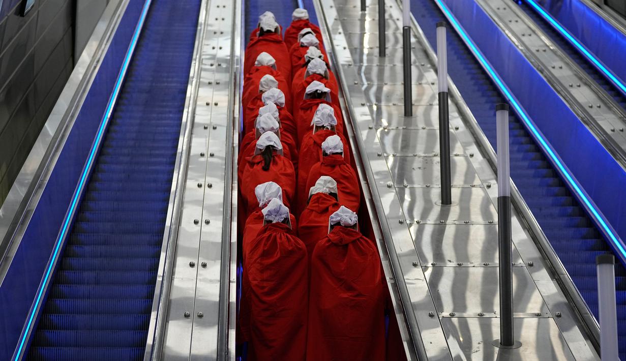 Pengunjuk rasa yang mendukung hak-hak perempuan berpakaian seperti karakter dari serial TV "The Handmaid's Tale" saat melakukan perjalanan untuk memprotes rencana pemerintah baru Perdana Menteri Benjamin Netanyahu untuk merombak sistem peradilan di sebuah stasiun kereta api di Yerusalem, Israel, 1 Maret 2023. Mengacu pada fenomena yang berkembang, harian Inggris The Guardian menggambarkan penampilan para pelayan sebagai salah satu simbol paling kuat dari protes feminis kontemporer. (AP Photo/Ohad Zwigenberg)