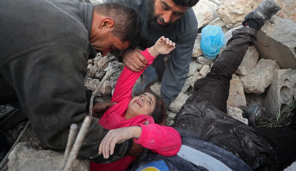 Anggota Syrian Civil Defence atau White Helmets berusaha menyelamatkan gadis yang tertimpa puing bangunan usai serangan udara pasukan pemerintah di Desa Tal Mardikh, Provinsi Idlib, Suriah, Kamis (19/12/2019). Pasukan Suriah kian intens menyerang Idlib. (Omar HAJ KADOUR/AFP)