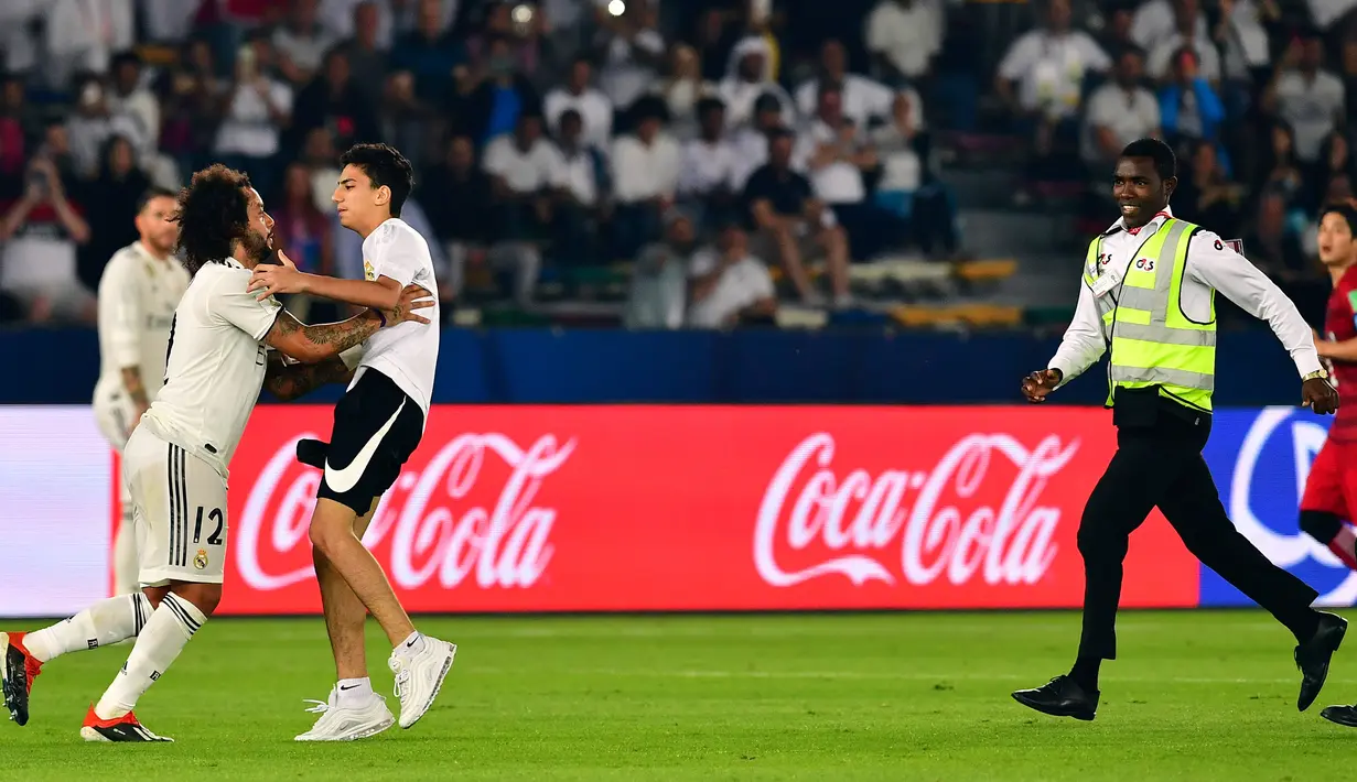 Seorang fans berusaha memeluk bek Real Madrid, Marcelo selama pertandingan semifinal Piala Dunia Antarklub 2018 antara Real Madrid melawan Kashima Antlers di stadion Zayed Sports City di Abu Dhabi, Uni Emirat Arab (19/12). (AFP Photo/Giuseppe Cacace)