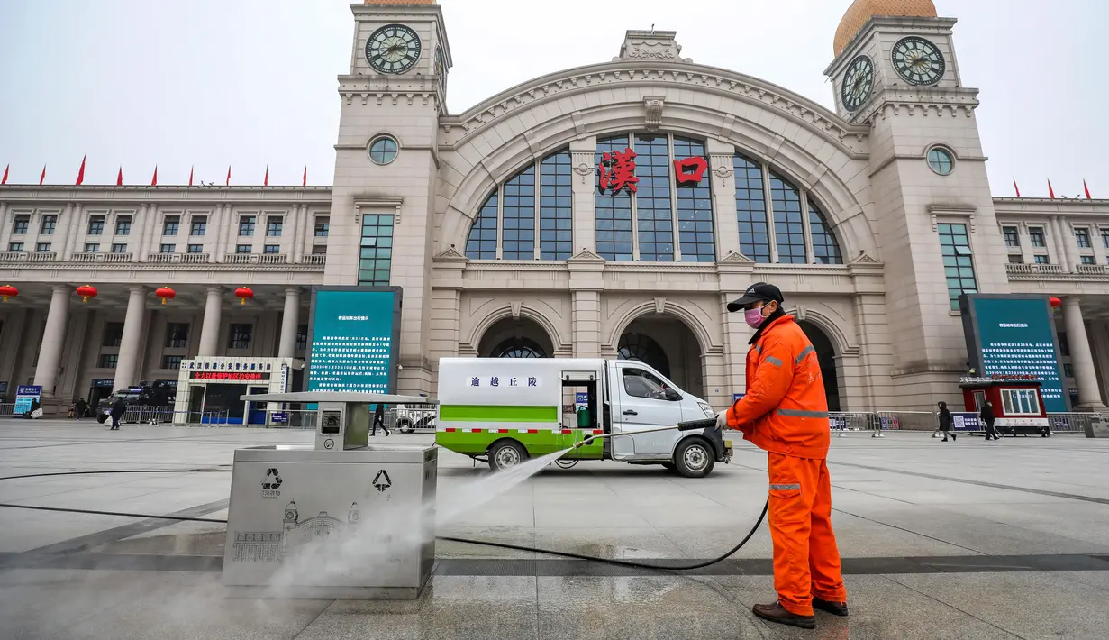 Pekerja menyemprot tempat sampah di luar Stasiun Kereta Api Hankou yang ditutup di Wuhan, Provinsi Hubei, China, Kamis (23/1/2020). Pemerintah China mengisolasi Kota Wuhan yang berpenduduk sekitar 11 juta jiwa untuk menahan penyebaran virus corona. (Chinatopix via AP)