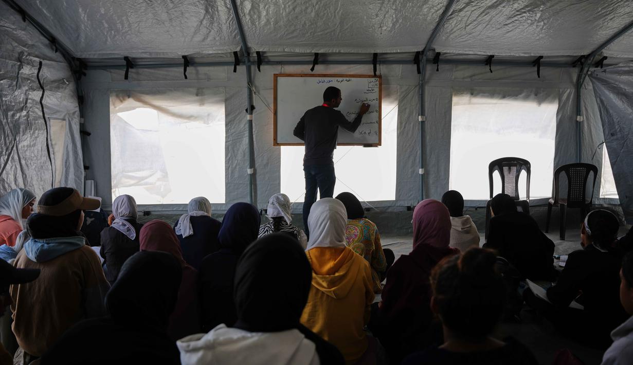 Badan PBB untuk Bantuan dan Pekerjaan bagi Pengungsi Palestina (UNRWA) diketahui telah membuka kembali beberapa sekolah di Gaza. Tampak dalam foto, para siswa Palestina mengikuti pelajaran di dalam tenda yang didirikan di pantai di Khan Younis, Jalur Gaza, Rabu, 12 November 2025. (AP Photo/Abdel Kareem Hana)