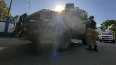 Seorang polisi nasional berbicara dengan rekan-rekannya di samping mobil polisi lapis baja di Port-au-Prince, Haiti, Sabtu (21/1/2023). Salah satu geng Haiti menyerbu bagian penting ibu kota, Port-Au-Prince, dan bertempur dengan polisi sepanjang hari, menyebabkan setidaknya tiga petugas tewas dan satu lainnya hilang. (AP Photo/Megan Janetsky)