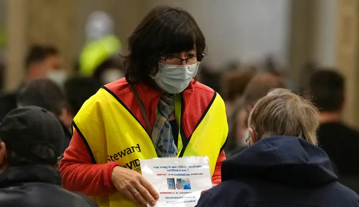 Petugas menunjukkan cara mengunduh sertifikat COVID-19 kepada warga usai mereka menerima booster vaksin COVID-19 Moderna di ruang tunggu pusat vaksinasi Antwerp Expo, Antwerp, Belgia, 27 Desember 2021. Warga Belgia meneima booster vaksin COVID-19 untuk mencegah Omicron. (AP Photo/Virginia Mayo)