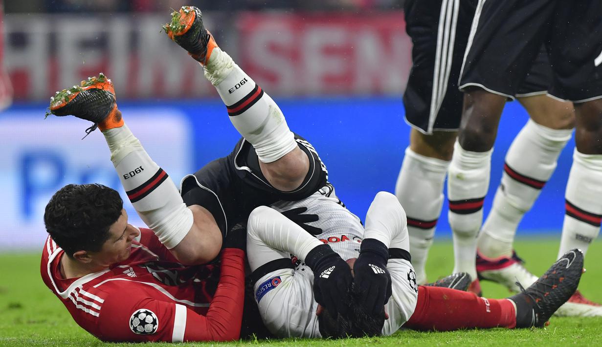 Bek Besiktas, Gary Alexis Medel Soto dan pemain Bayern Munchen, Robert Lewandowski terjatuh saat berebut bola pada pertandingan pertama babak 16 besar Liga Champions di Allianz Arena, Selasa (20/2). Bayern menang telak dengan skor 5-0 (Thomas KIENZLE/AFP)