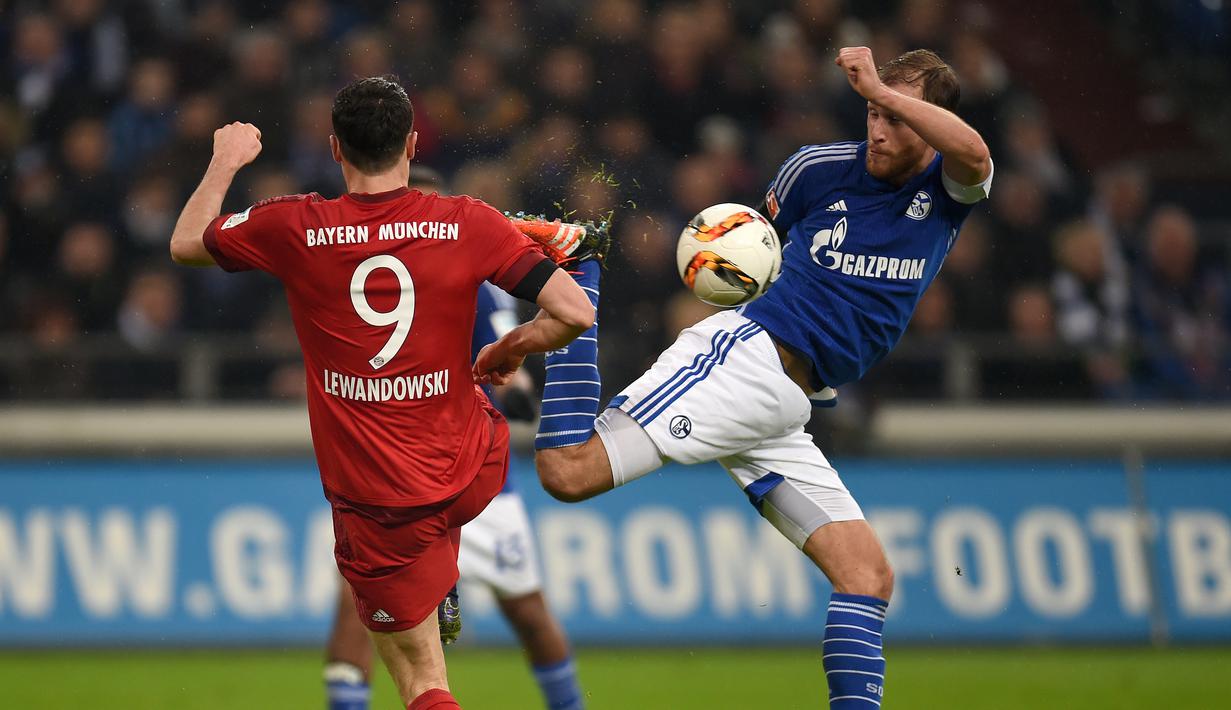 Pemain Bayern Munich Robert Lewandowski (kiri) berebut bola dengan pemain  Schalke 04  Benedikt Hoewedes pada lanjutan Bundesliga di Gelsenkirchen, Jerman,Minggu (22/11/2015) dini hari WIB. Bayern Munich  menang 3-1.   (AFP Photo/Patrik Stollarz)