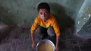 Seorang anak Palestina yang mengungsi duduk di samping sepanci sup miju-miju yang ia terima di sebuah titik distribusi makanan di Kota Gaza di Jalur Gaza utara pada 25 Juli 2025. (Omar AL-QATTAA/AFP)