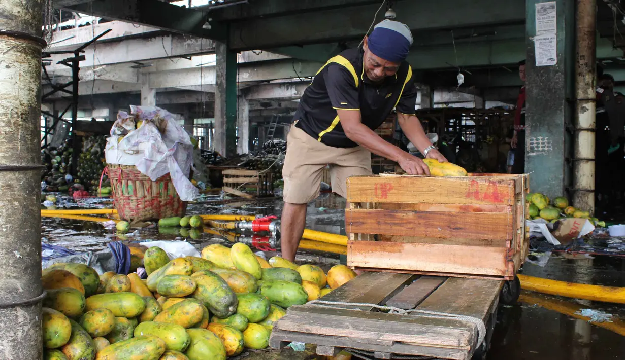 Beberapa pedagang masih berupaya menyelamatkan dagangan yang tersisa dari amukan si jago merah. Tampak dalam foto, pedagang berupaya menyelamatkan sisa dagangannya setelah api yang membakar Pasar Induk Kramat Jati Jakarta berhasil dipadamkan pada Senin (15/12/2025). (merdeka.com/magang/Rendi Saputra)