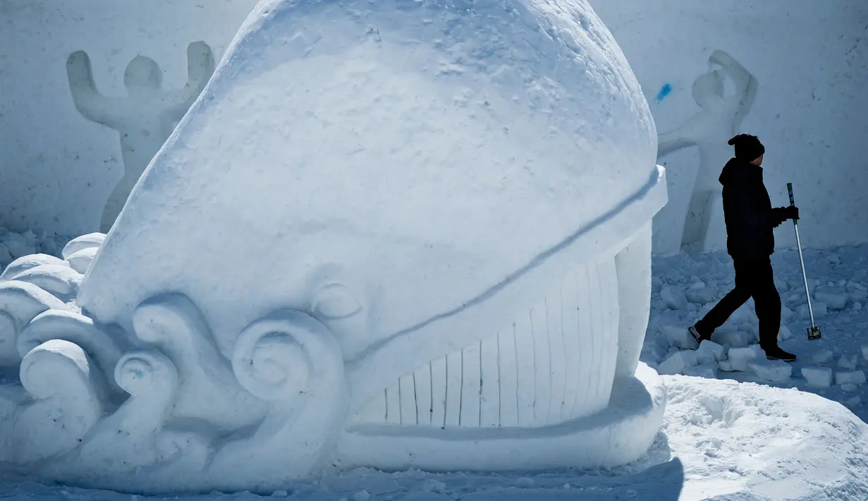 Seorang seniman mengukir patung es raksasa berbentuk ikan di Snow Land, PyeongChang, Korea Selatan, Senin (5/2). (Brendan Smialowski/AFP)