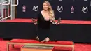 Penyanyi Mariah Carey berpose setelah membuat cetakan tangannya di TCL Chinese Theatre di Los Angeles, AS (1/11). Penyanyi 47 tahun ini mendapat penghargaan membuat cetakan tangan dan kaki di TCL Chinese Theatre. (Photo by Jordan Strauss/Invision/AP)