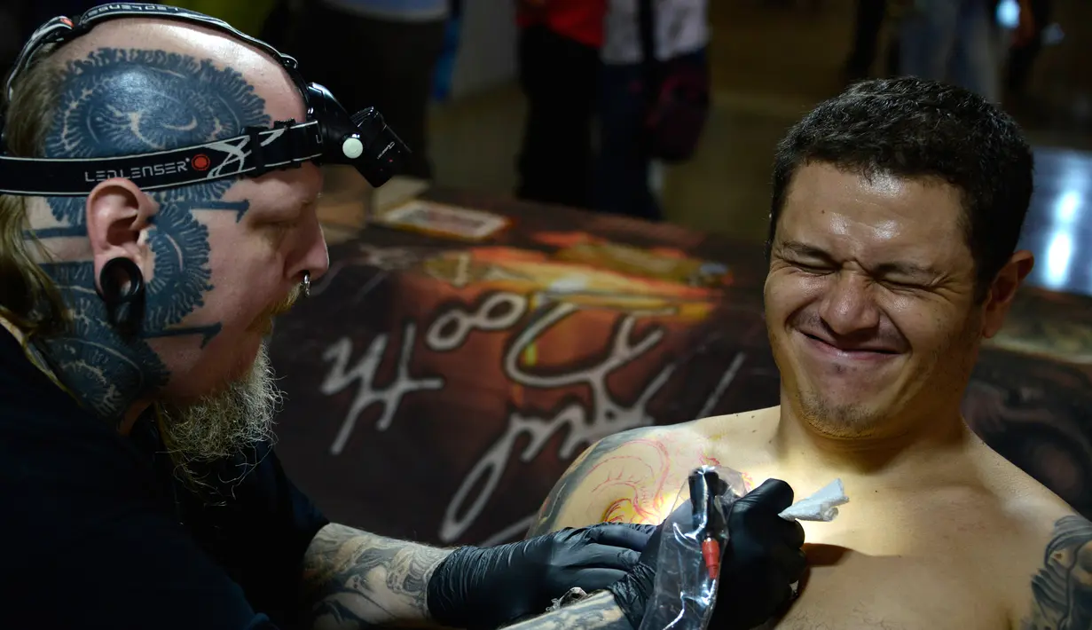 Pengunjung terlihat kesakitan saat ditato oleh seniman Paul Booth di edisi 5 Konvensi Internasional Paradise Tatto, di San Antonio de Belen, San Jose, (8/5). Lebih dari 300 seniman tato berpartisipasi di acara ini.(AFP PHOTO/Ezequiel Becerra)