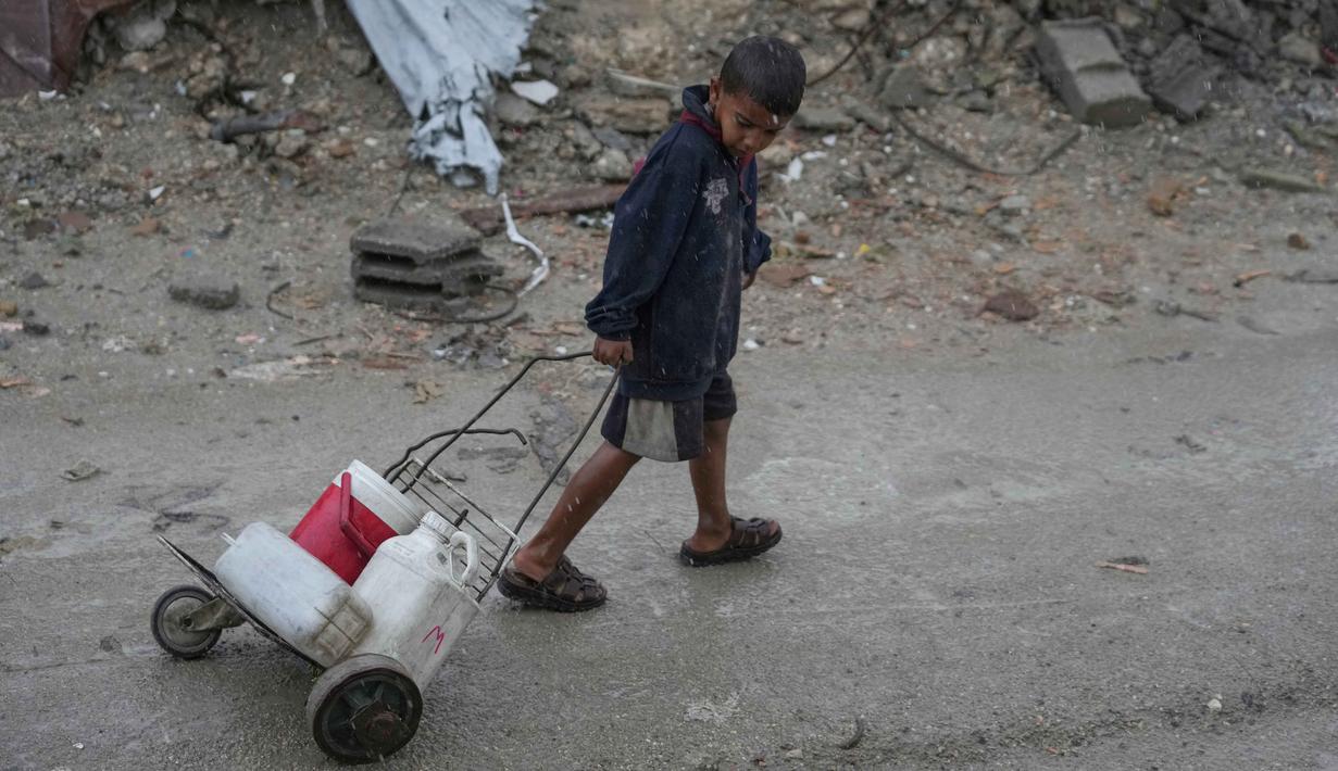 Kekurangan air bersih memiliki konsekuensi yang sangat fatal bagi anak-anak di Gaza, di antaranya dehidrasi dan malnutrisi, munculnya beragam penyakit, hingga kehilangan nyawa. Tampak dalam foto, seorang anak laki-laki menarik gerobak buatan sendiri yang diisi dengan jerigen plastik berisi air di kawasan Sheikh Radwan, Kota Gaza, pada Jumat 14 November 2025. (AP Photo/Jehad Alshrafi)