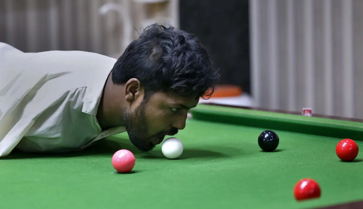 Mohammad Ikram bermain snooker dengan dagunya di sebuah klub snooker lokal di kota Samundri, Pakistan, Minggu (25/10/2020). Ikram, 32, lahir tanpa lengan, tetapi semua orang mengagumi keterampilan snookernya ketika dia memukul bola dengan dagunya di atas meja snooker. (AP Photo/Anjum Naveed)
