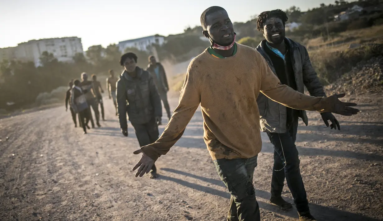 Para migran berjalan setelah melintasi pagar yang memisahkan kantong Spanyol Melilla dari Maroko, di Melilla, Spanyol (3/3/2022). Pemerintah Spanyol di Melilla mengatakan 380 dari 1.200 migran berhasil mengatasi penghalang ganda 6 meter (20 kaki) yang mengelilingi kota. (AP Photo/Javier Bernardo)