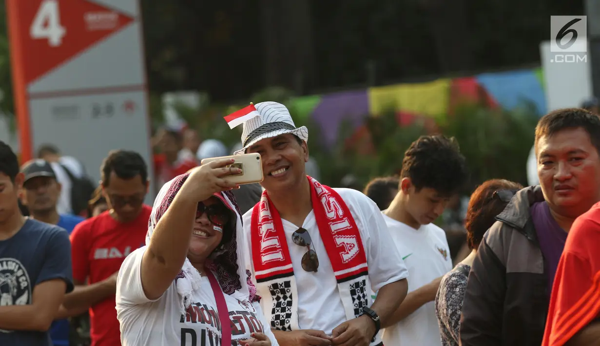 Calon penonton berswafoto sambil antre untuk mendapatkan tiket final bulu tangkis beregu putra di sekitar tiket boks di kawasan GBK, Jakarta, Rabu (22/8). Final bulu tangkis beregu putra mempertemukan Indonesia vs China. (Liputan6.com/Helmi Fithriansyah)
