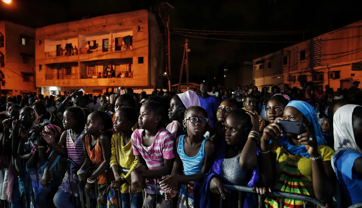 Para remaja Senegal menonton pertunjukan Dakar Fashion Week di lingkungan Niari Tali, (9/6). Menurut data Euromonitor dunia fashion di Sub-Sahara Afrika telah berkembang pesat selama dua dekade terakhir. (AP Photo / Finbarr O'Reilly)